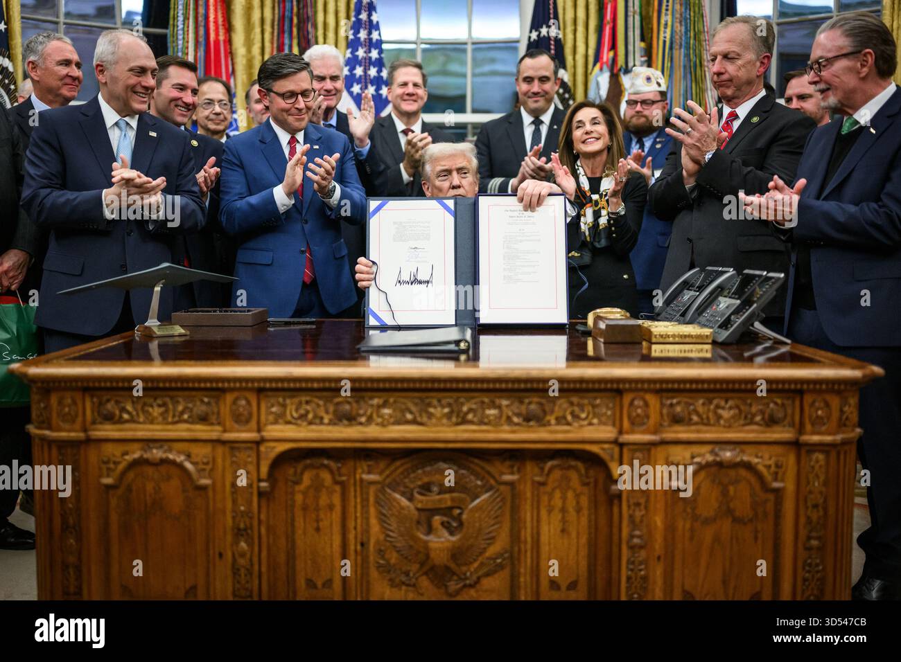 Il presidente Donald Trump mostra ai membri dei media il disegno di legge firmato dal Congresso che riapre il governo, mercoledì 12 novembre 2025, nell'Ufficio ovale. (Foto ufficiale della Casa Bianca di Daniel Torok) Foto Stock