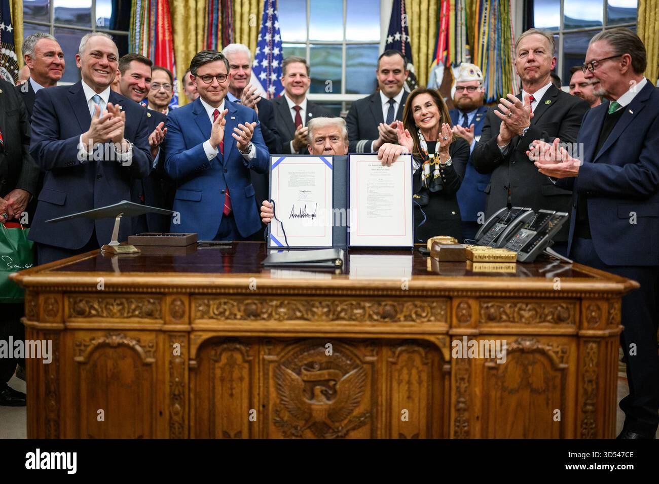 Il presidente Donald Trump mostra ai membri dei media il disegno di legge firmato dal Congresso che riapre il governo, mercoledì 12 novembre 2025, nell'Ufficio ovale. (Foto ufficiale della Casa Bianca di Daniel Torok) Foto Stock