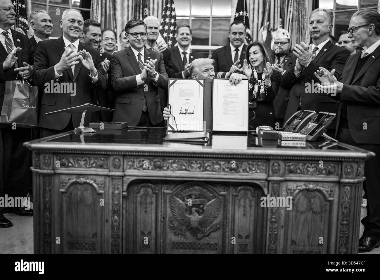 Il presidente Donald Trump mostra ai membri dei media il disegno di legge firmato dal Congresso che riapre il governo, mercoledì 12 novembre 2025, nell'Ufficio ovale. (Foto ufficiale della Casa Bianca di Daniel Torok) Foto Stock