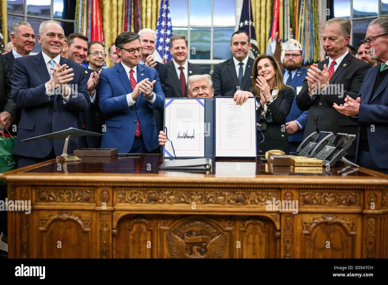 Il presidente Donald Trump mostra ai membri dei media il disegno di legge firmato dal Congresso che riapre il governo, mercoledì 12 novembre 2025, nell'Ufficio ovale. (Foto ufficiale della Casa Bianca di Daniel Torok) Foto Stock