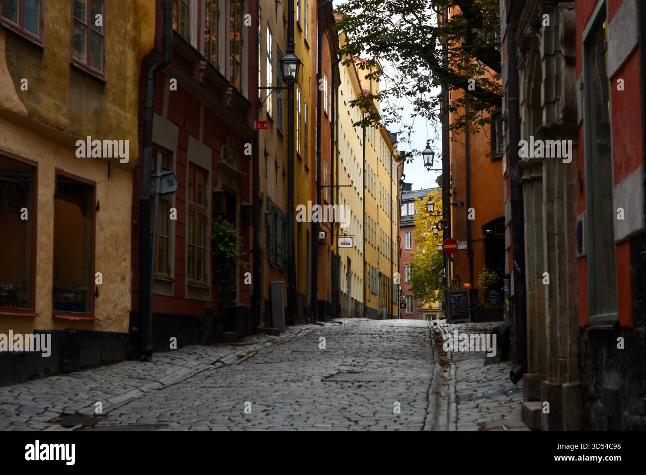 Città vecchia di Stoccolma, Svezia, una stretta strada acciottolata costeggiata da colorati edifici storici in un giorno d'autunno. Foto Stock