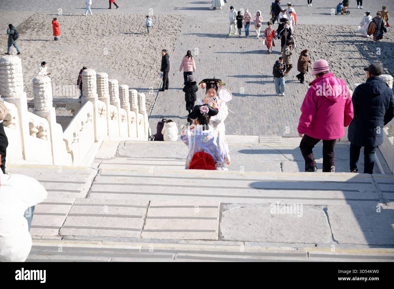 Gli amici in hanfu si fermano sui gradini del palazzo mentre uno si siede a posare e l'altro incornicia lo scatto alla città Proibita Foto Stock