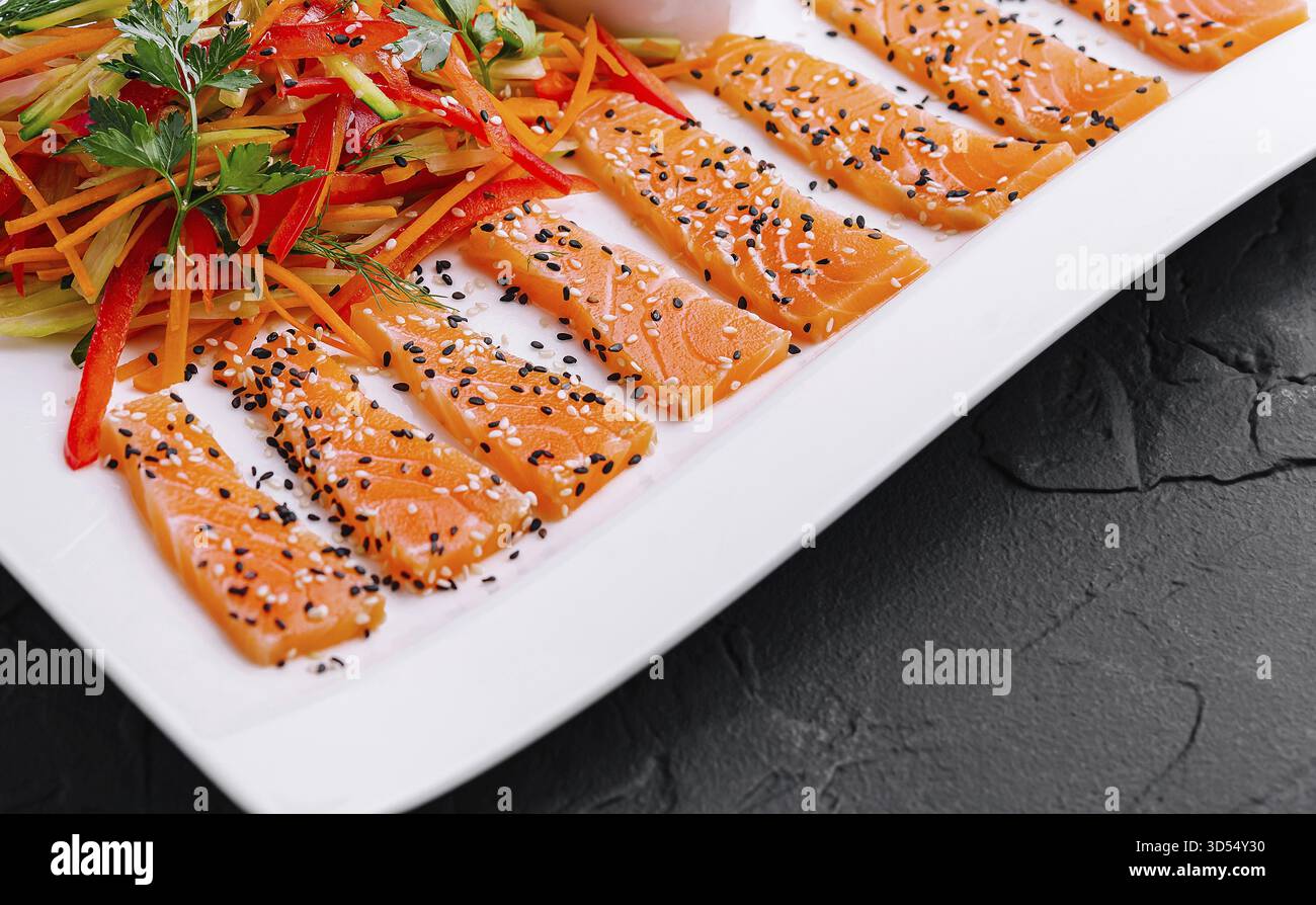 Cibo, fette di salmone con insalata di carote e peperoni e salsa di soia - cucina asiatica Foto Stock