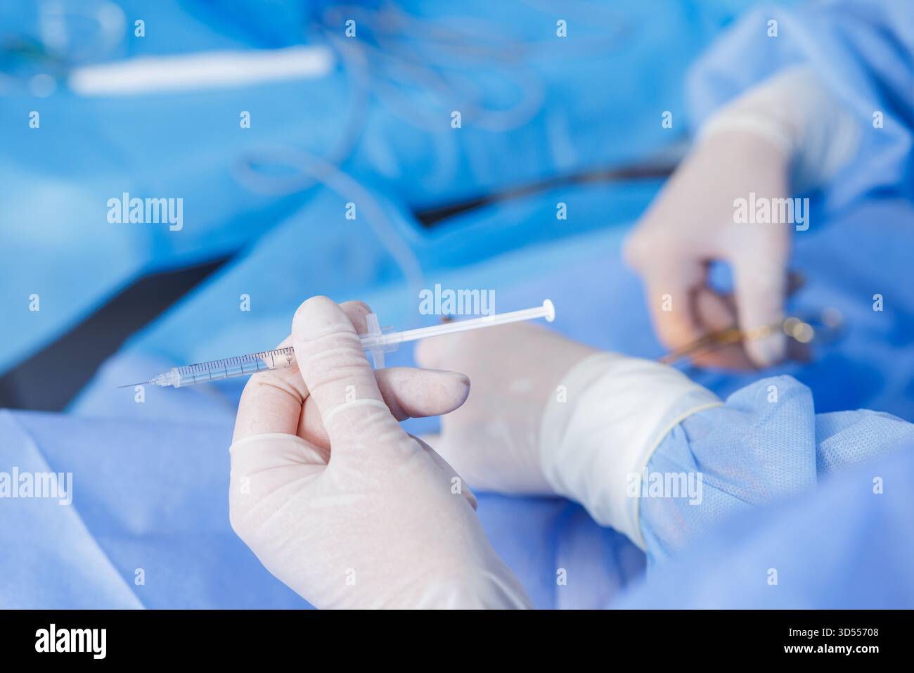 Primo piano della siringa con i guanti di tenuta con anestetico durante le procedure chirurgiche sterili nella moderna sala operatoria dell'ospedale Foto Stock