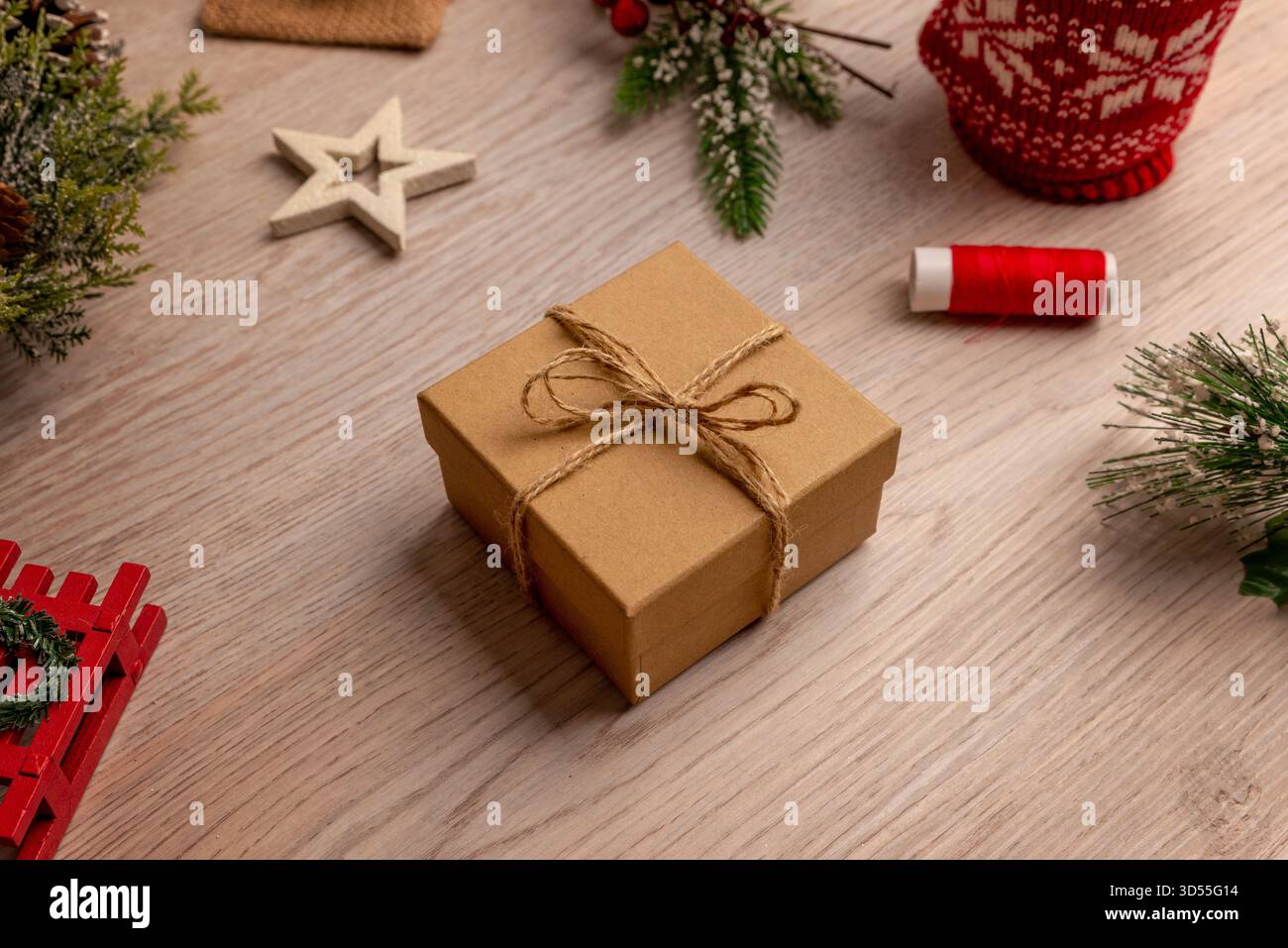 Confezione regalo fatta a mano con spago circondata da materiali di artigianato natalizio, perfetta per esercitazioni fai da te, laboratori creativi e ispirazione artigianale stagionale Foto Stock