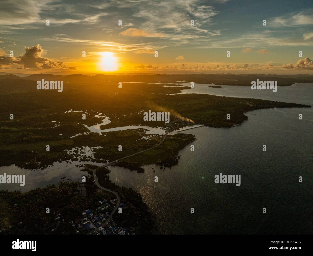 Il tramonto proietta una luce dorata sulla costa, sull'estuario del fiume e su isole lontane lungo l'orizzonte. Siargao, Filippine. Foto Stock