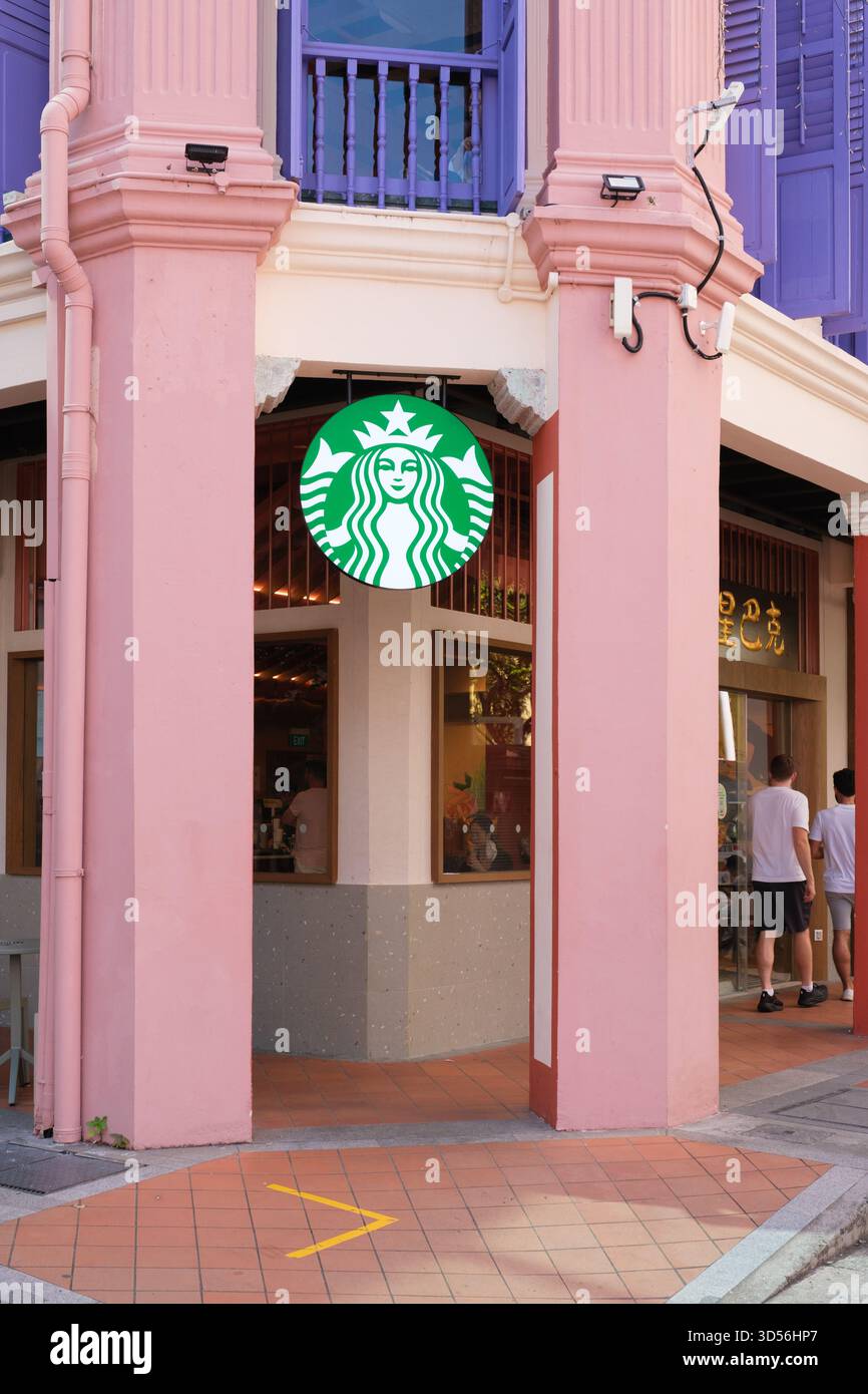 Singapore, Singapore - 3 ottobre 2025: Una caffetteria Starbucks si trova all'angolo di un edificio colorato caratterizzato da colonne rosa e persiane viola Foto Stock