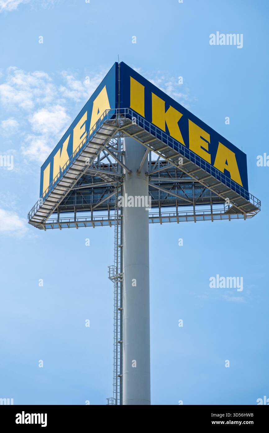 Un palo alto presenta un grande cartello IKEA con lettere gialle luminose, che mostra con orgoglio il marchio del rivenditore di nuovo cielo blu Foto Stock