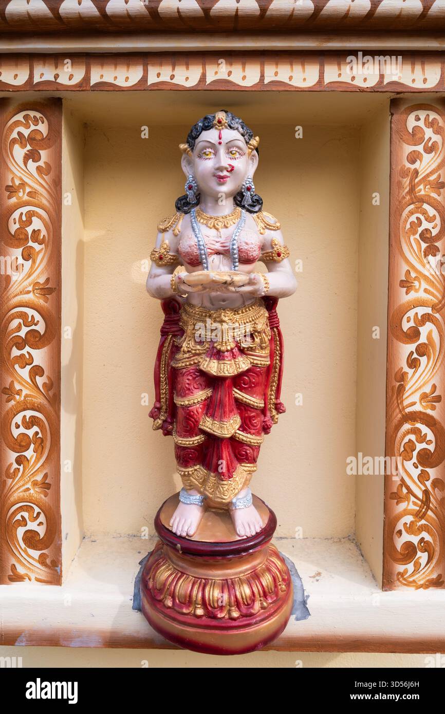 Una statua della divinità indù splendidamente realizzata adorna l'alcova di un tempio locale, riflettendo l'intricata arte e l'importanza culturale Foto Stock