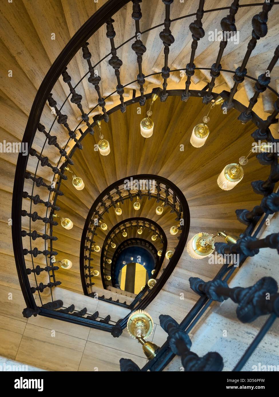 Vista dall'alto, scala tortuosa con balaustra in metallo scuro e lampade in ottone che creano un suggestivo motivo a spirale Foto Stock