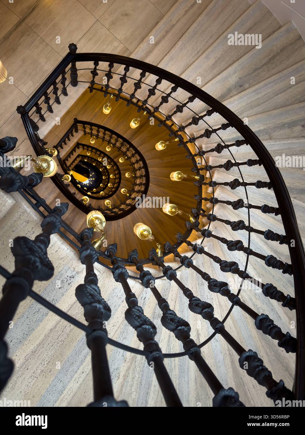 La scala a chiocciola interna balaustra in ferro nero le lampadine calde lungo la curva creano una prospettiva spettacolare e un'eleganza architettonica che invitano lo spettatore nel grande spazio Foto Stock