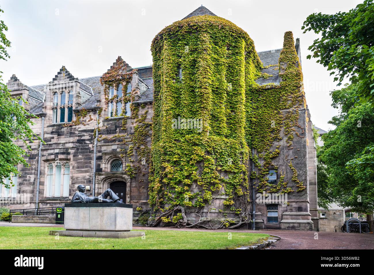 Aberdeen, Scozia, Regno Unito - 7 luglio 2024: Statua del giovane uomo lounge presso il New Kings Lecture Building, festeggiato in Green Ivy. Università di Aberdeen, Scotla Foto Stock