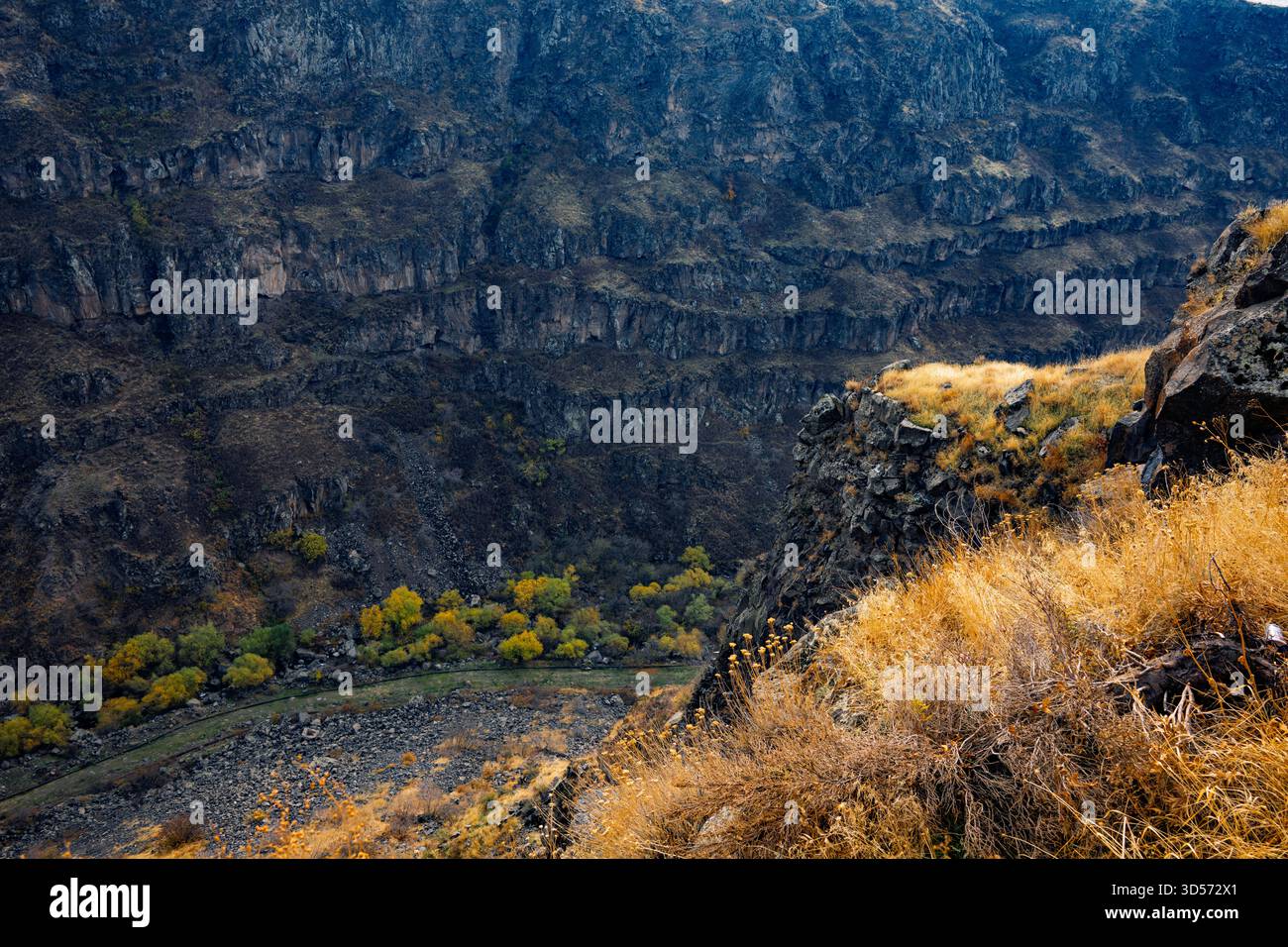 Una catena montuosa con un fiume che la attraversa. Il fiume è marrone e le montagne sono marrone e grigio Foto Stock