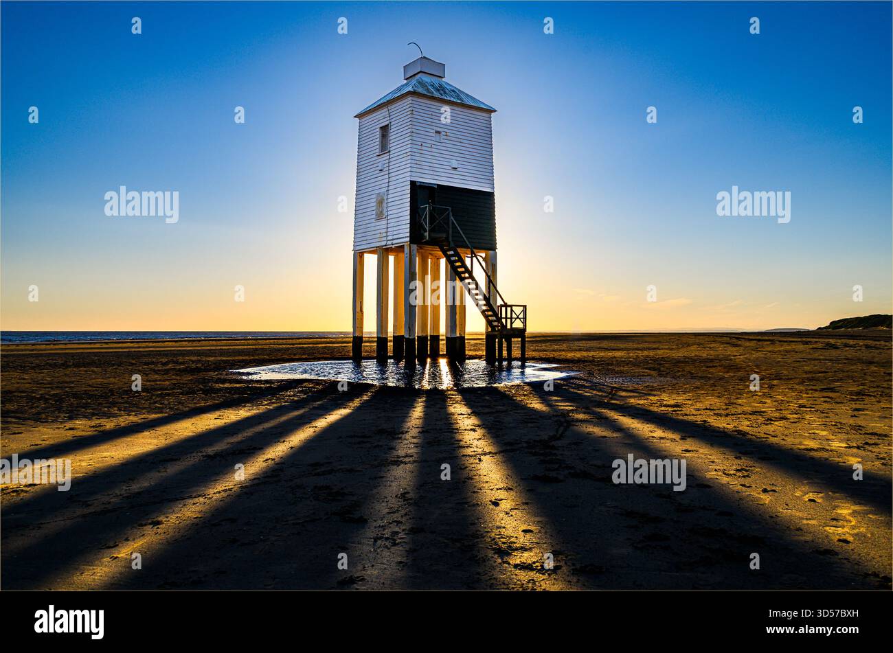Vista del faro basso di Burnham-on-Sea al tramonto, creando pozzi di luce e ombra attraverso le gambe del faro Foto Stock