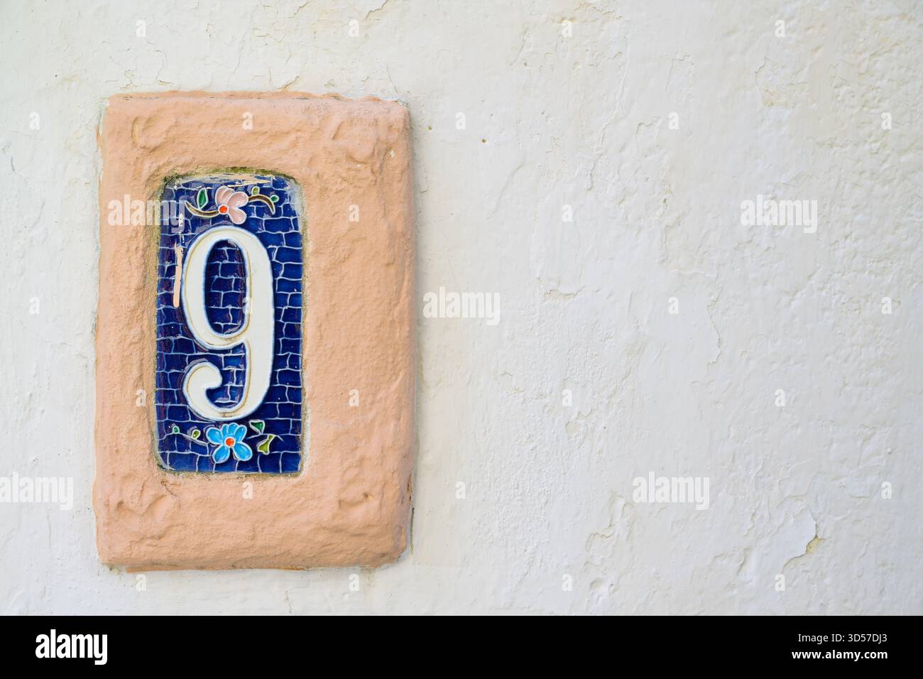 Piastrella decorativa in ceramica che mostra il numero nove su una parete testurizzata, con spazio di copia. Foto Stock