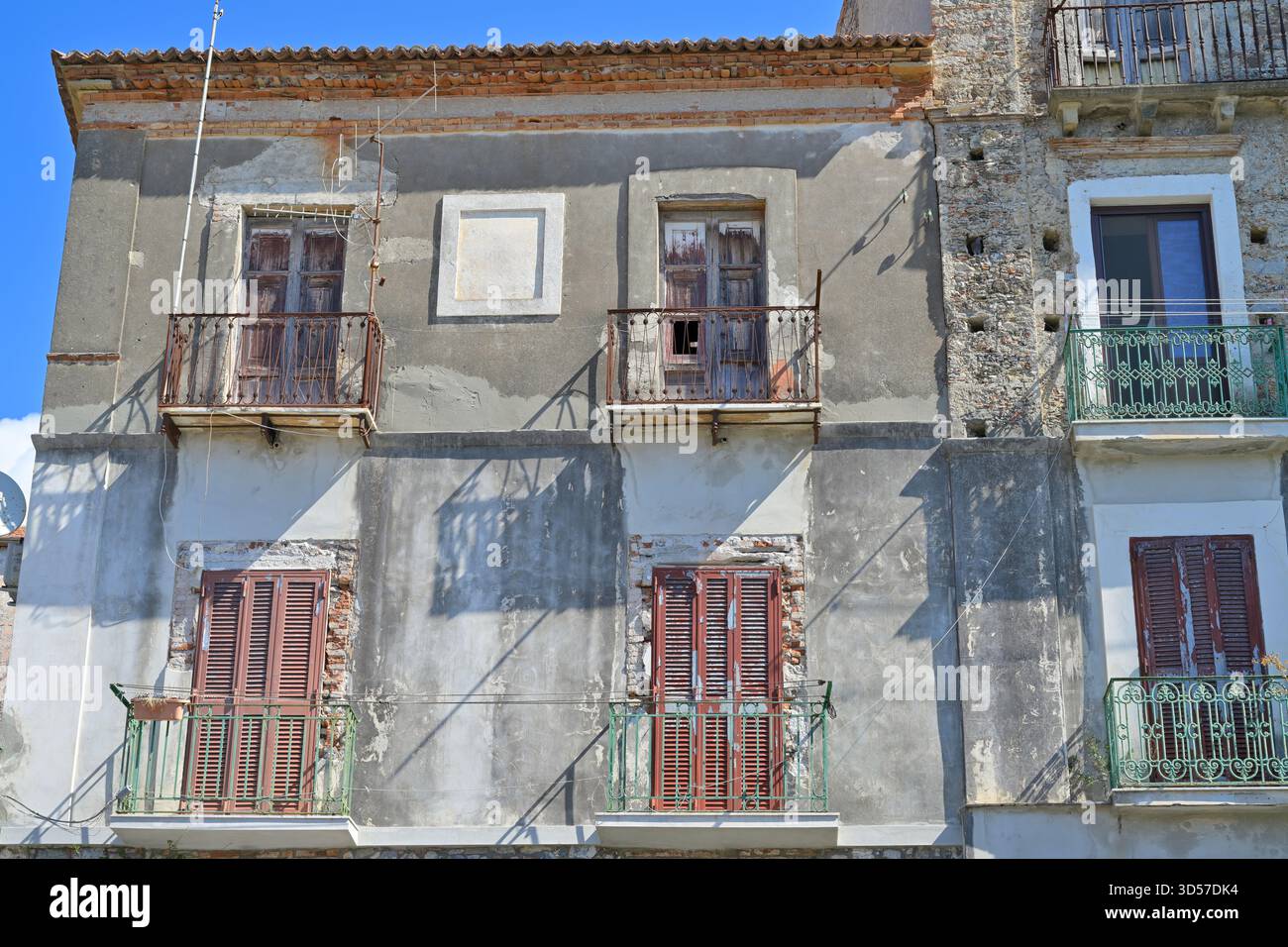 La facciata dell'edificio era intempestiva, con balconi danneggiati e vecchie persiane, che mostravano decadenza e abbandono. Foto Stock