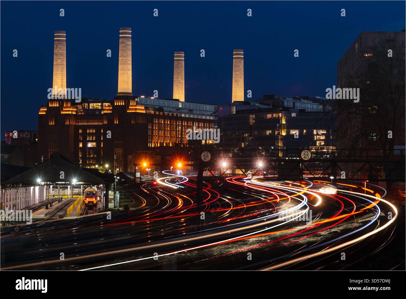 Vista notturna della centrale elettrica di Battersea attraverso le linee ferroviarie con sentieri leggeri Foto Stock