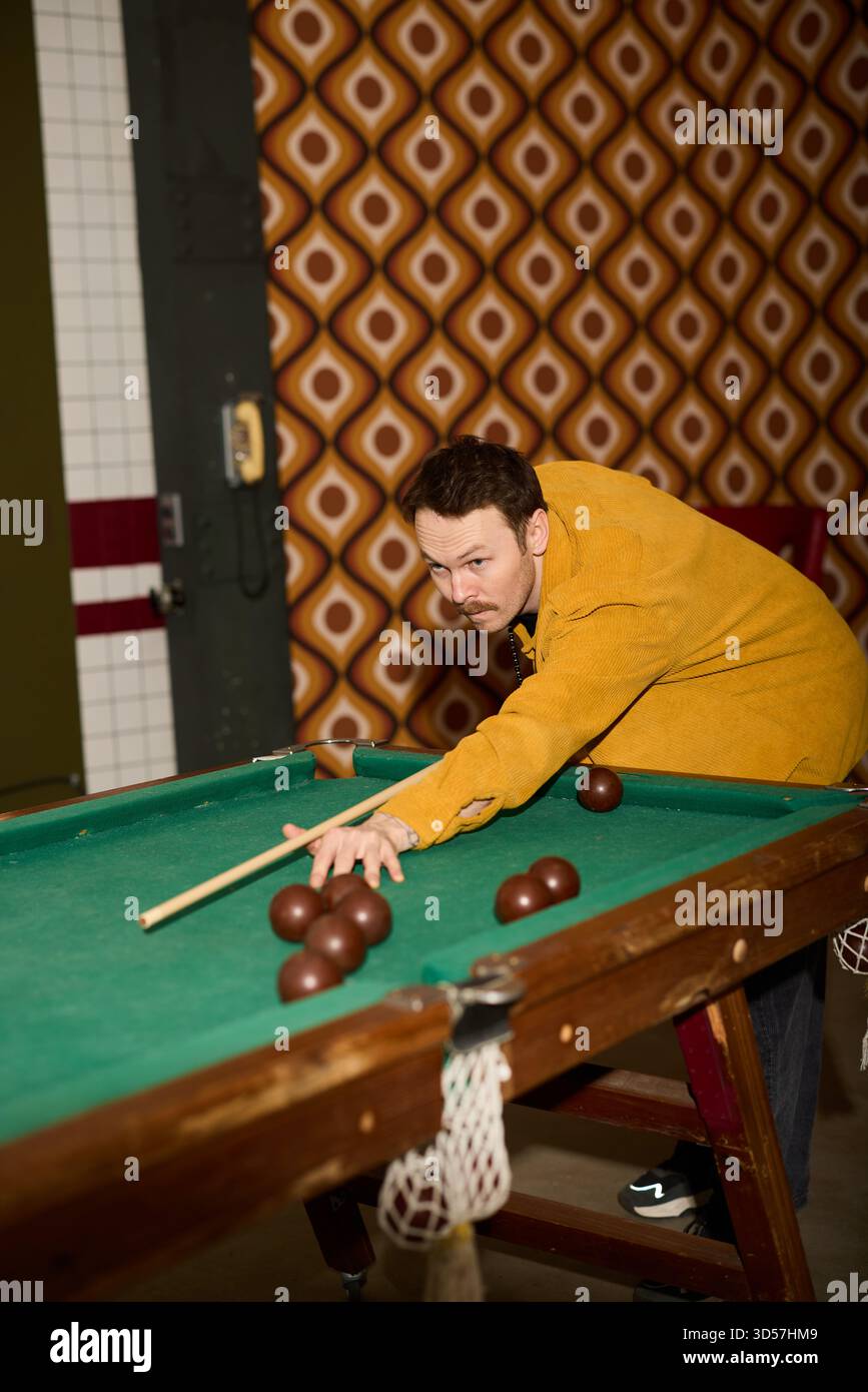 Uomo che gioca a biliardo in un ambiente vintage con arredamento retrò Foto Stock