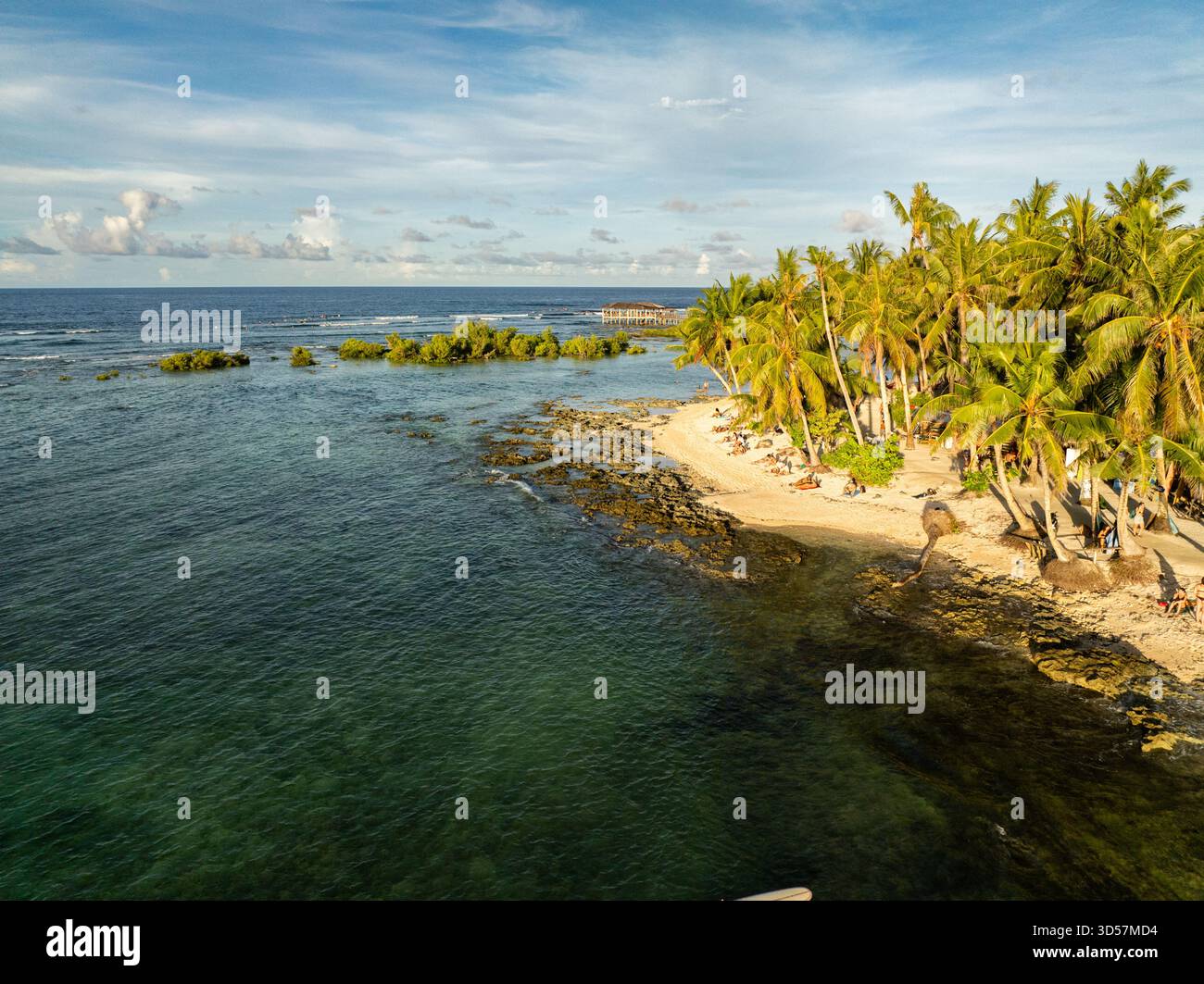 Spiaggia di sabbia tropicale con alte palme e costa rocciosa che incontrano il mare. Siargao, Filippine. Foto Stock