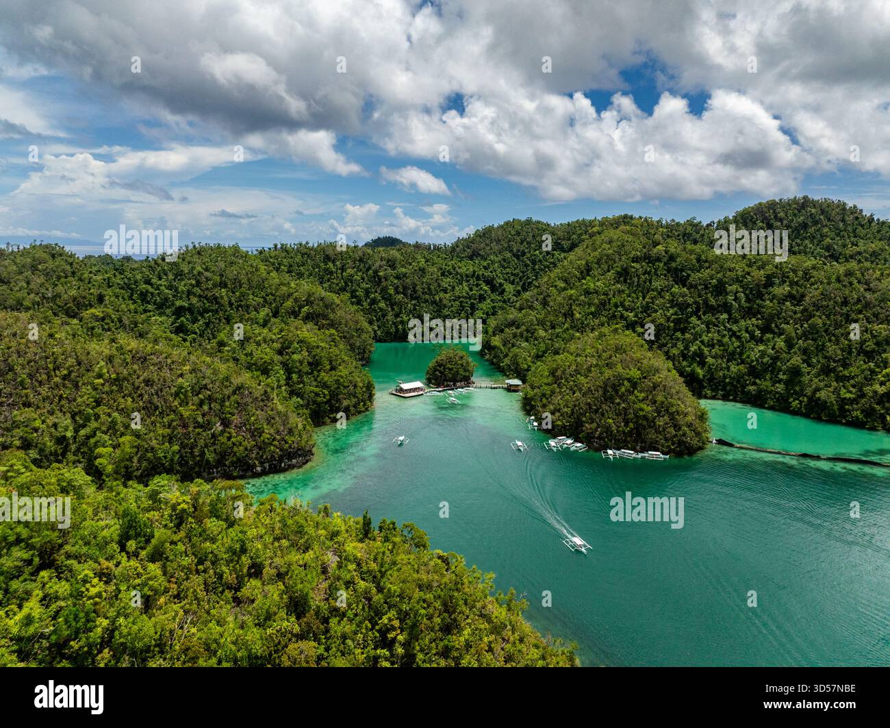 Le barche bianche navigano attraverso le acque turchesi della laguna incorniciate da colline boscose. Siargao, Filippine. Laguna blu di Sugba. Foto Stock