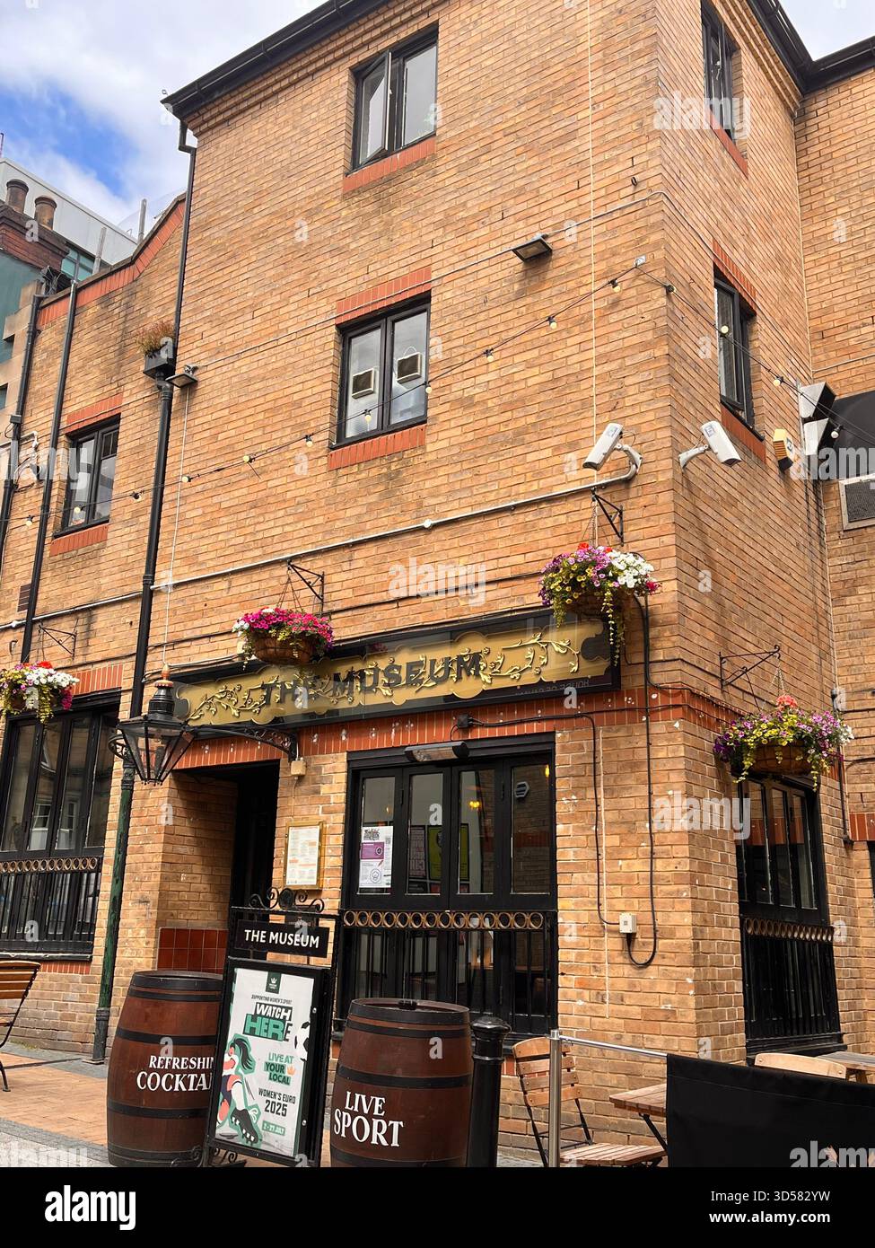 Un affascinante pub in mattoni a Hull, Inghilterra, caratterizzato da cesti di fiori appesi, insegne vintage e una calda e tradizionale atmosfera. L'edificio è rustico Foto Stock