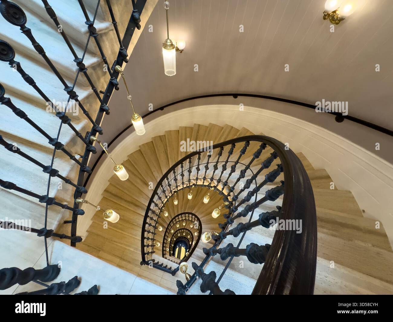 Scala a chiocciola, ringhiera decorata, luci a sospensione calde, design circolare, interni di grande impatto Foto Stock