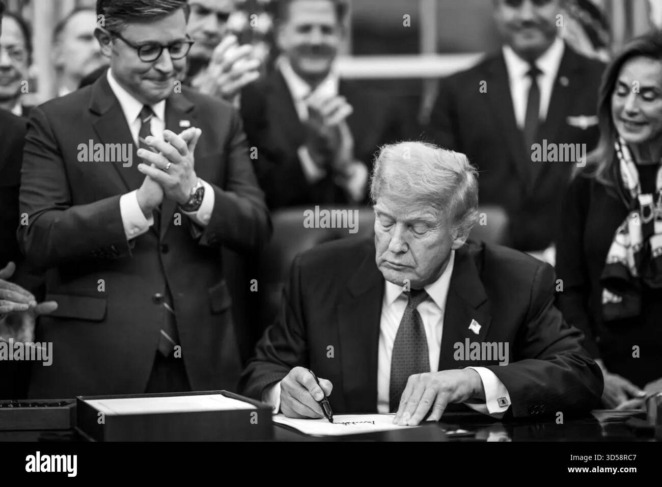 Il presidente Donald J. Trump firma il disegno di legge per riaprire il governo degli Stati Uniti nell'Ufficio ovale, circondato da funzionari applaudenti. Washington, D.C., 12 novembre 2025. Per gentile concessione della Casa Bianca. Foto Stock