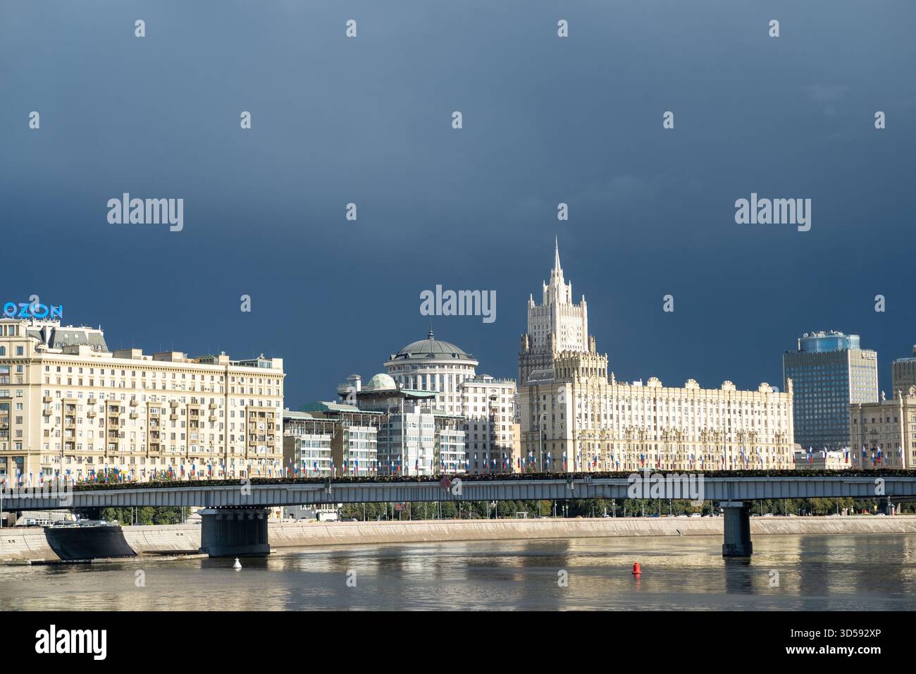 25 agosto 2025, Mosca, Russia. Lo skyline mostra una serie di stili architettonici, con una guglia visibile tra nuvole scure sul fiume Foto Stock