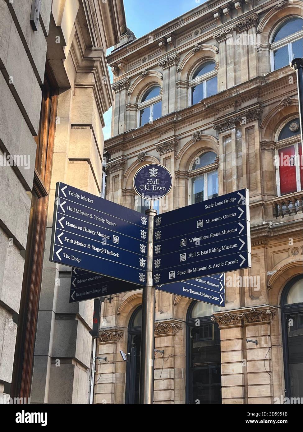 Un cartello blu direzionale posizionato vicino agli edifici storici in pietra di Hull, Inghilterra. La scena mette in risalto la combinazione di design urbano funzionale e Foto Stock