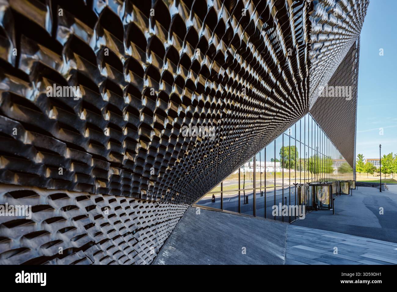 Vista ravvicinata di una suggestiva facciata architettonica moderna a Katowice, Polonia. L'edificio presenta uno schema dinamico di pannelli metallici e riflettenti Foto Stock