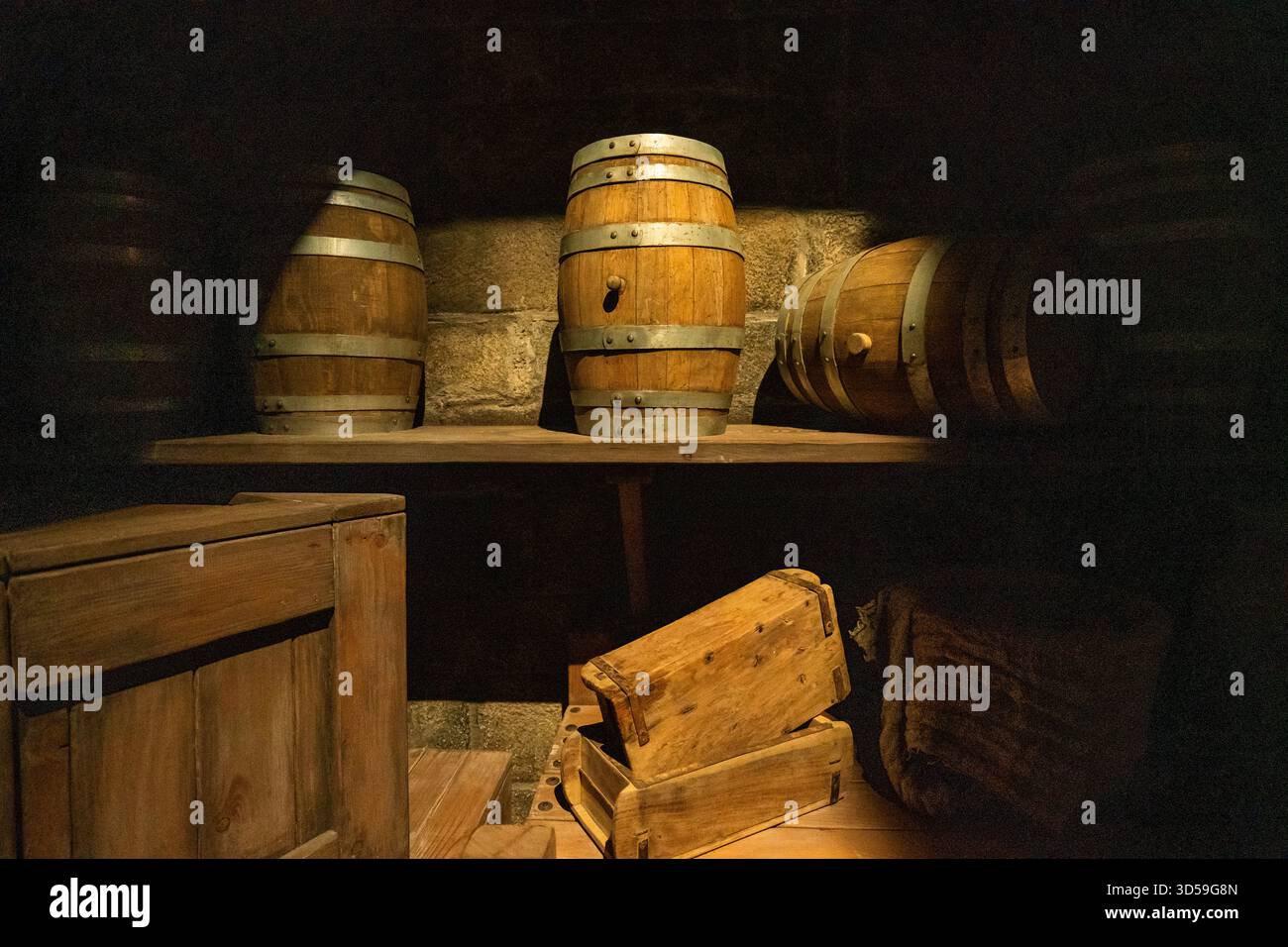 Botti e casse di legno rustiche esposte in una cantina poco illuminata ad Abu Dhabi, Emirati Arabi Uniti. L'illuminazione calda e le texture vecchie creano un vecchio stile Foto Stock