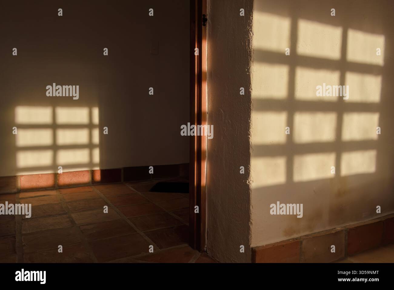 L'ombra di una finestra in pannelli di legno proiettata sulle pareti dalla luce del tramonto, in una casa colonica sulle montagne andine orientali Foto Stock