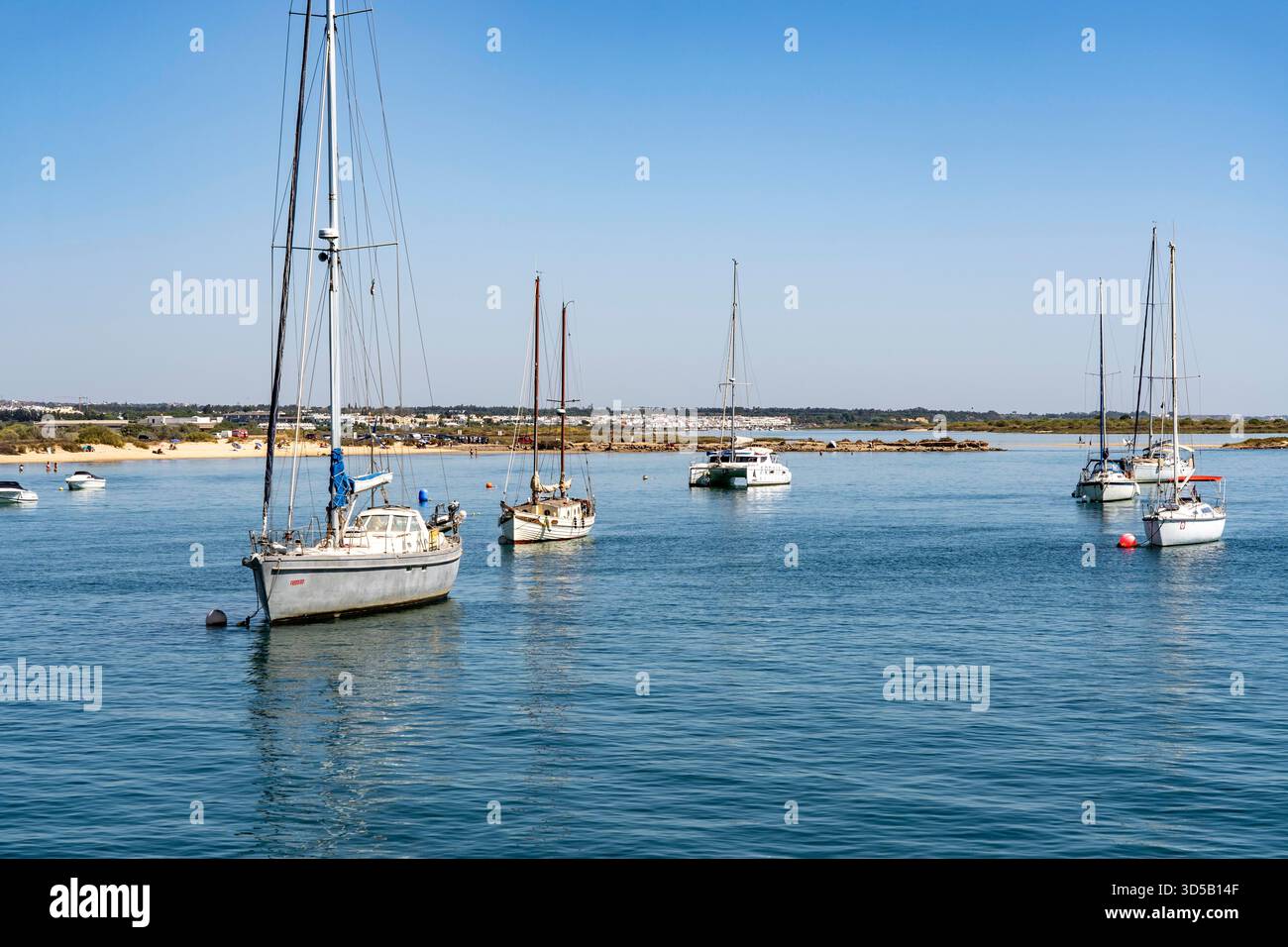 Barche a vela ancorate nel fiume Gilão, al largo della spiaggia di Praia da Ilha de Tavira, sull'isola al largo di Tavira, Algarve, Portogallo Foto Stock