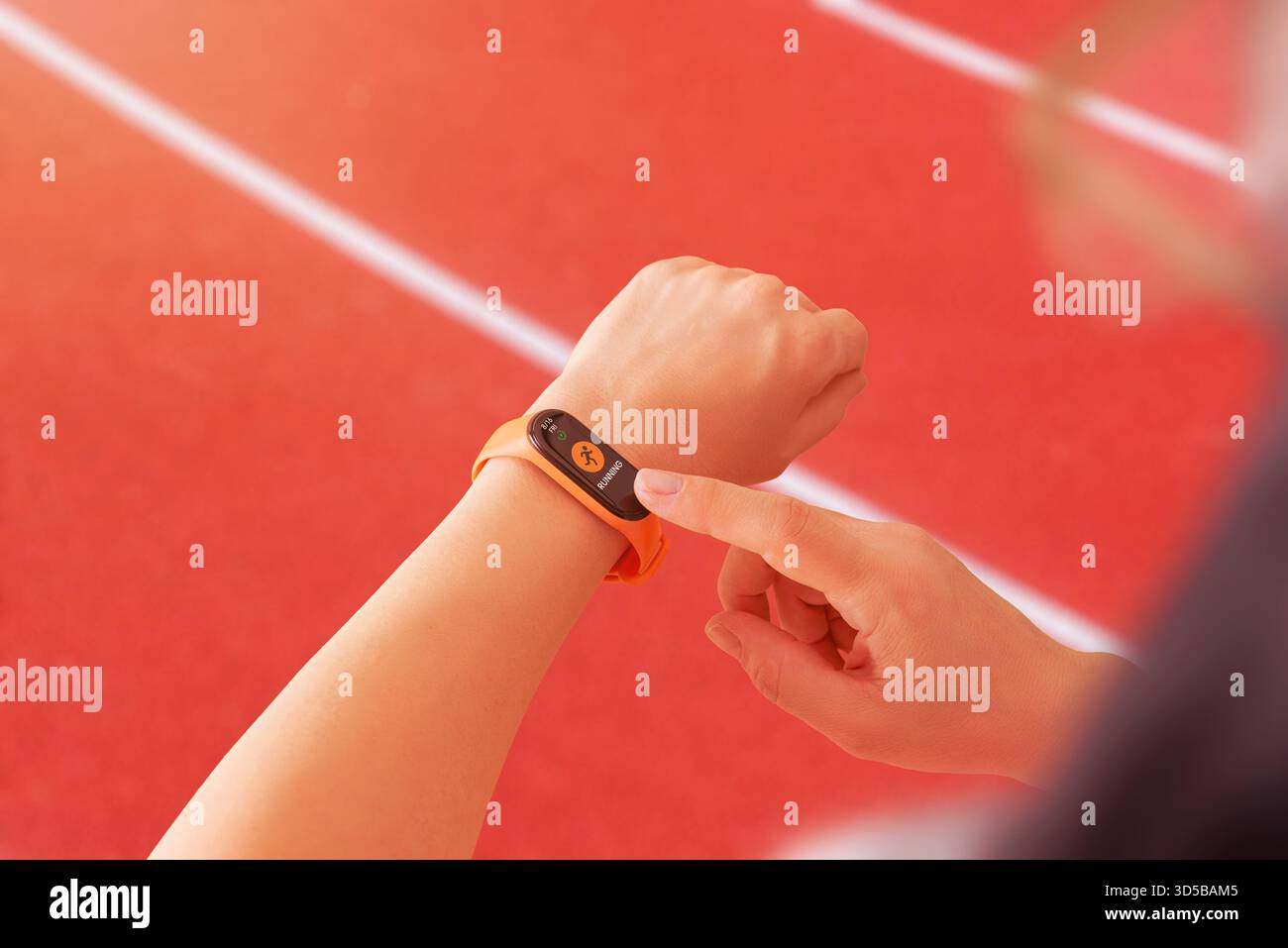 Smart band impostata sulla modalità running su una pista atletica, sottolineando il monitoraggio delle prestazioni sportive e le routine di allenamento attivo Foto Stock