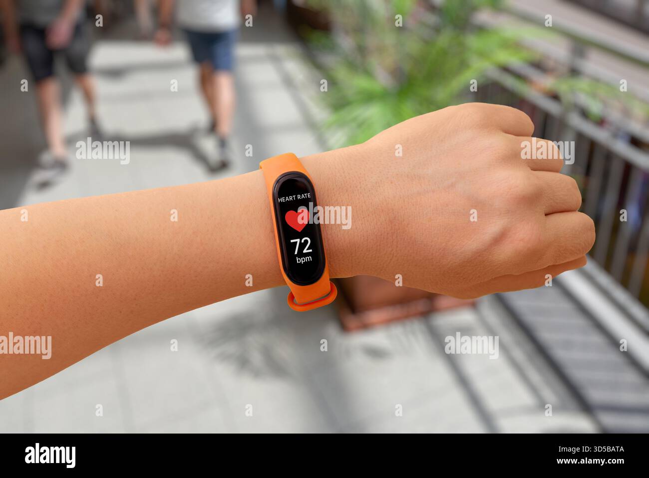 Banda intelligente che mostra la misurazione della frequenza cardiaca in un centro commerciale, evidenziando il monitoraggio della salute durante le attività quotidiane Foto Stock
