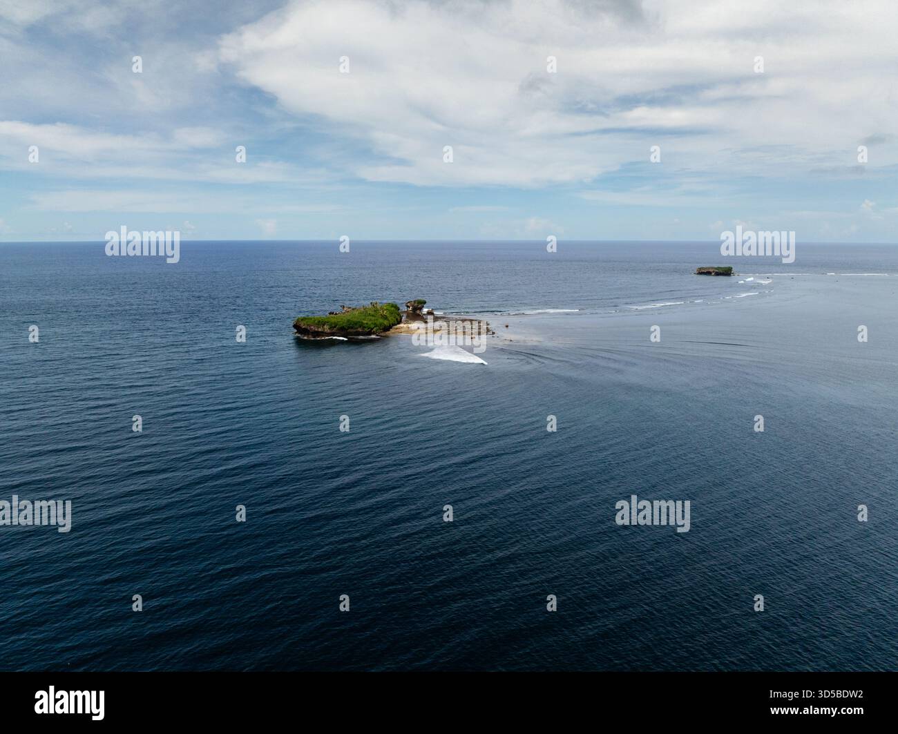 Isola rocciosa con vegetazione lussureggiante circondata da onde oceaniche in acque tropicali cristalline. Siargao, Filippine. Foto Stock