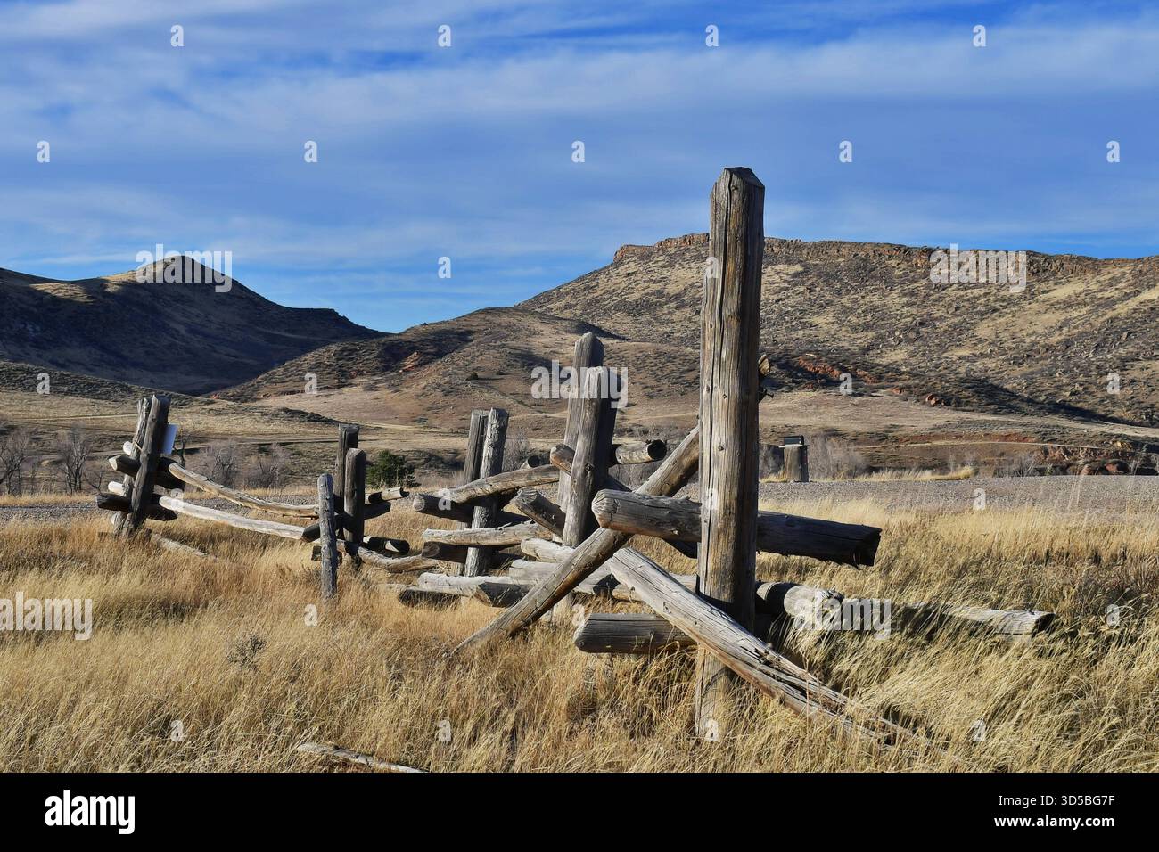 Recinzione a palo in legno nella campagna del Nord America, intemprata dalla neve del Wyoming, dalla pioggia e dal sole. Si fonde con il colore delle colline ora in autunno. Foto Stock