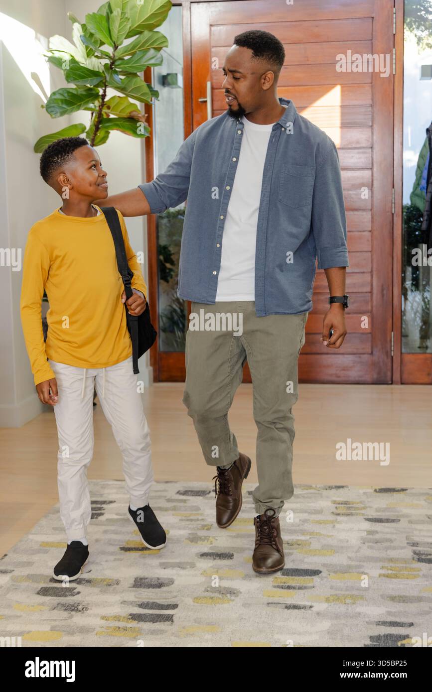 Padre e figlio camminano insieme a casa, sorridono e si legano prima della scuola Foto Stock