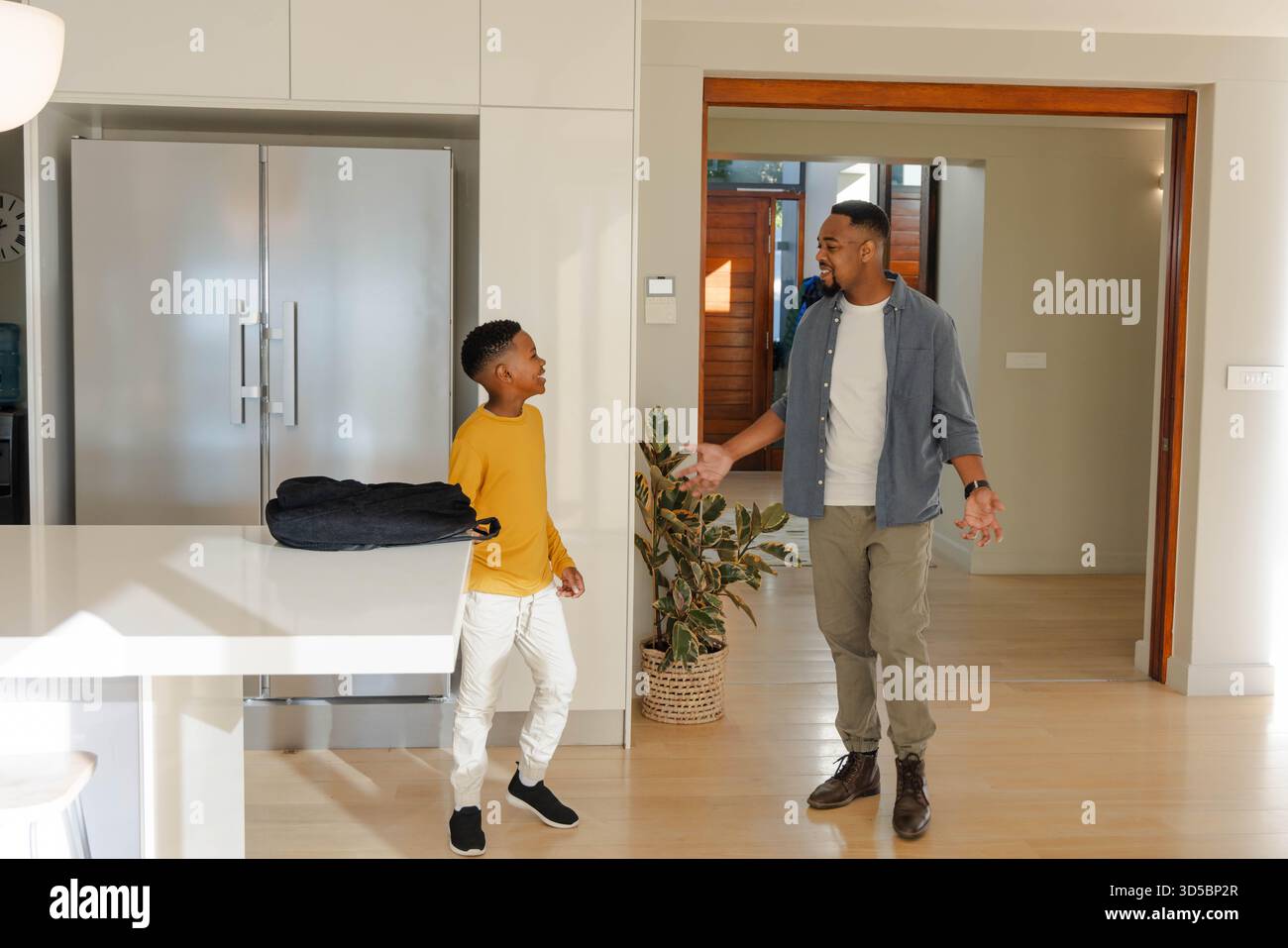 Padre e figlio che parlano in una cucina moderna e si godono momenti di qualità insieme Foto Stock