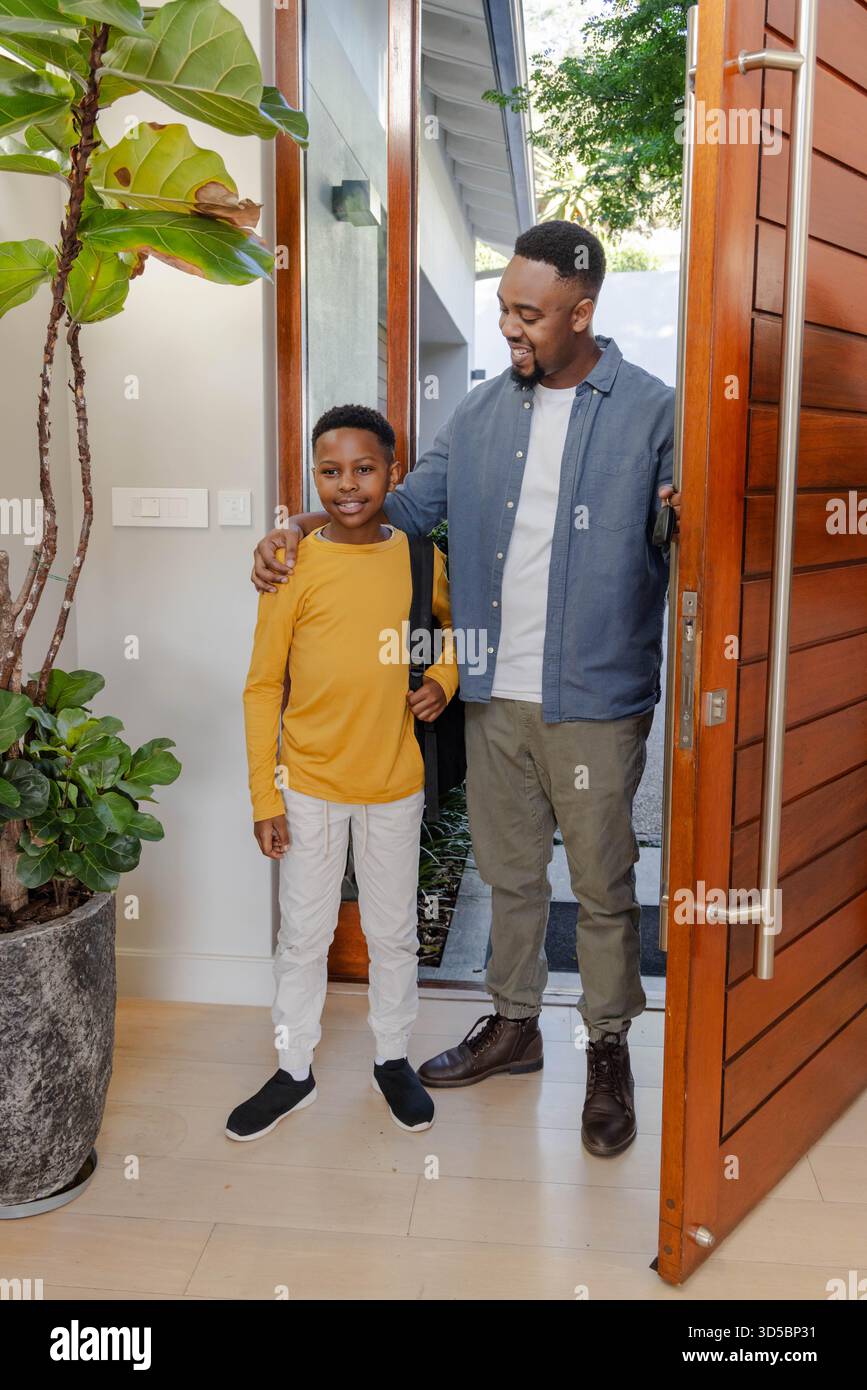 Padre e figlio sorridono, escono di casa per andare a scuola, si sentono emozionati e felici Foto Stock