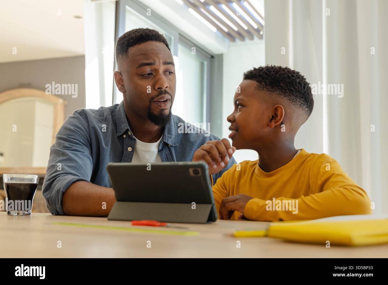 Padre e figlio che usano il tablet a casa, si impegnano nell'apprendimento insieme Foto Stock
