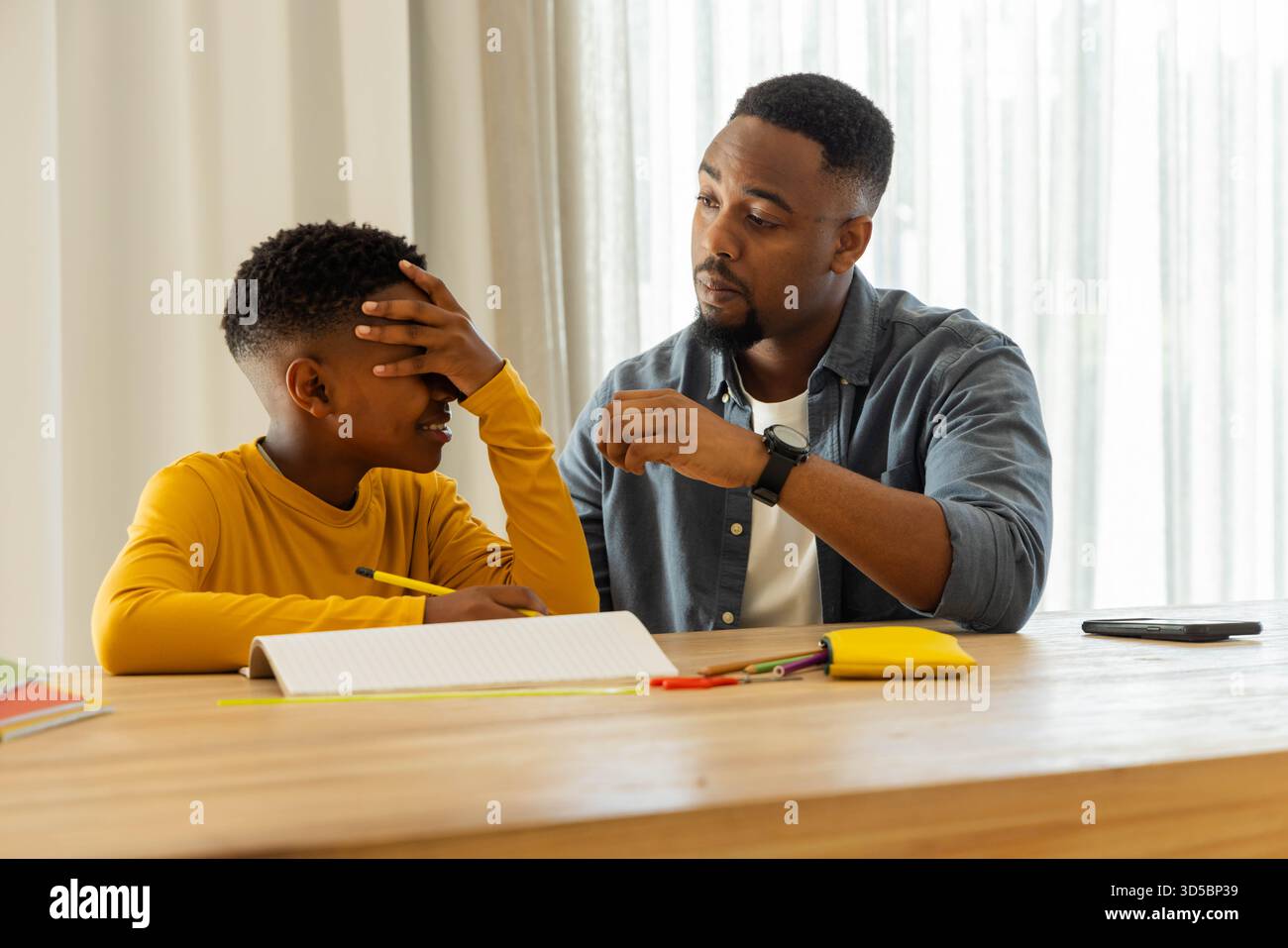 Padre che aiuta il figlio con i compiti a casa, offrendo assistenza e supporto Foto Stock
