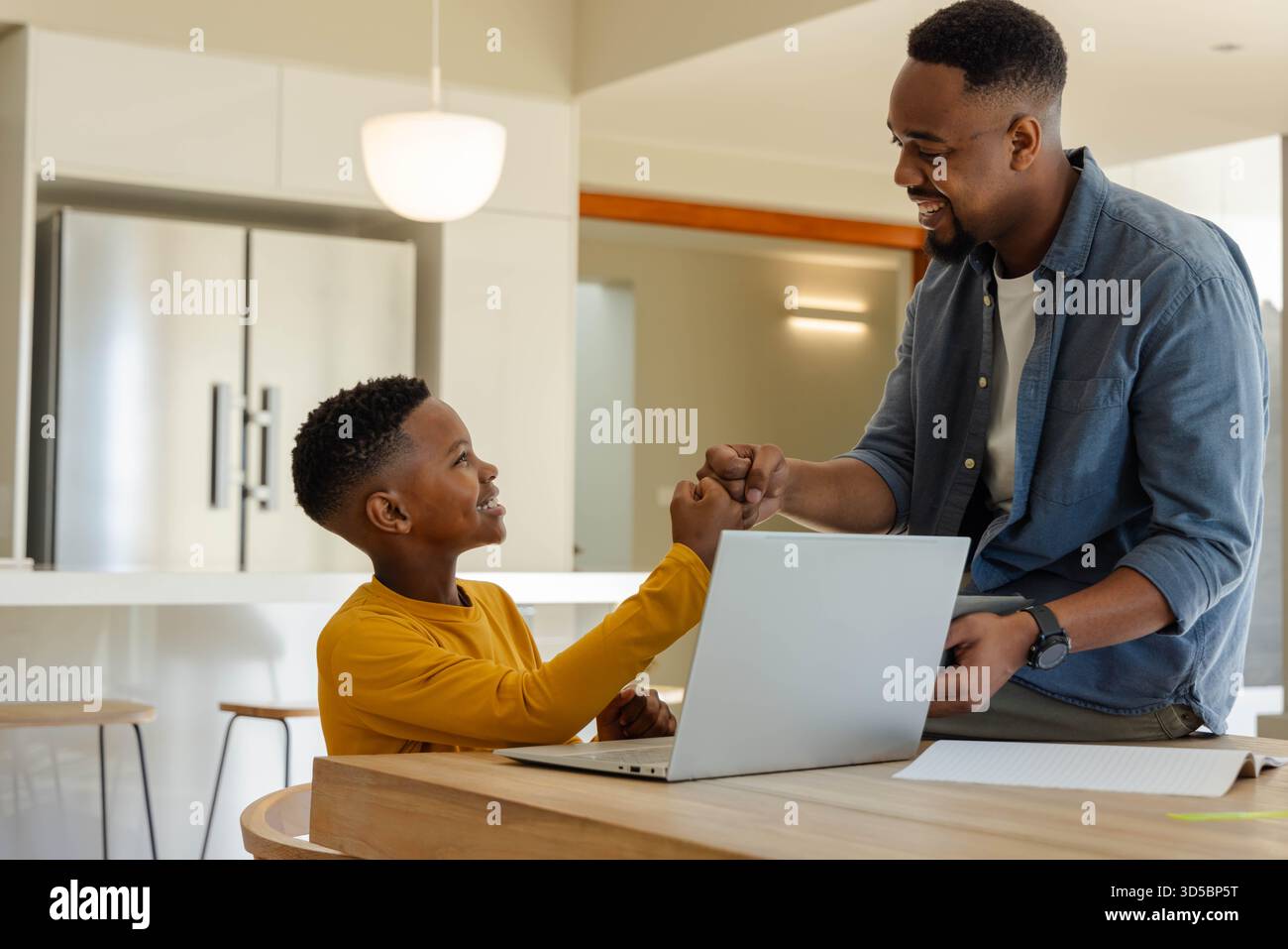 Padre e figlio si legano a casa, si urtano mentre si usano i laptop insieme Foto Stock