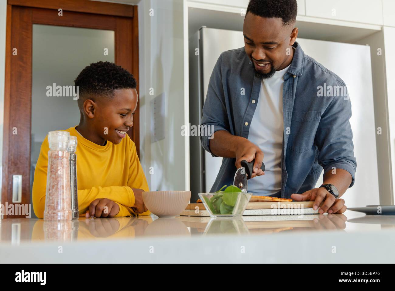 Padre e figlio afro-americani che amano cucinare insieme in una cucina moderna Foto Stock