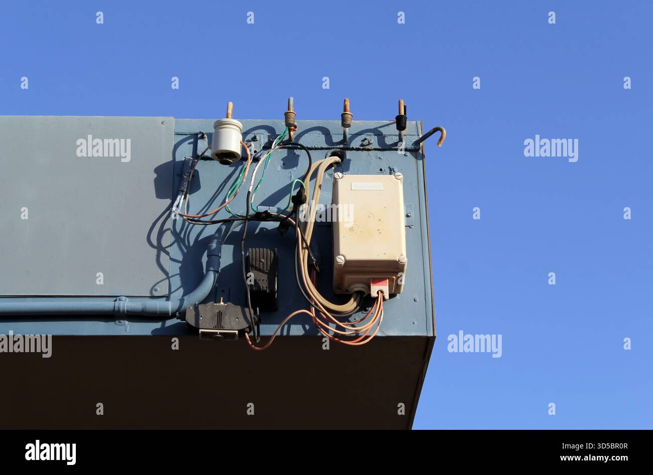 Apparecchiature elettriche fissate al tetto di un edificio contro un cielo azzurro Foto Stock