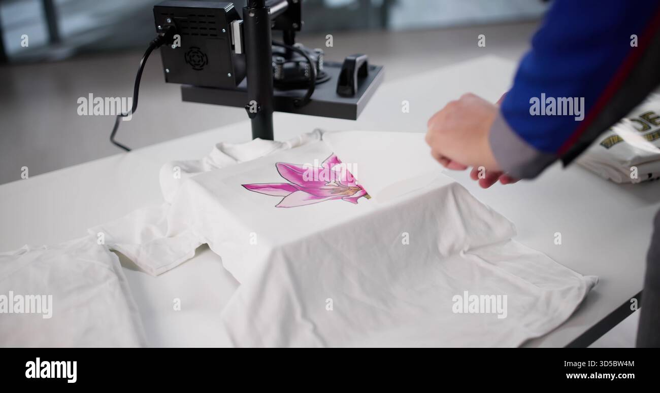 Uomo che crea magliette personalizzate all'officina di stampa a caldo. Foto Stock