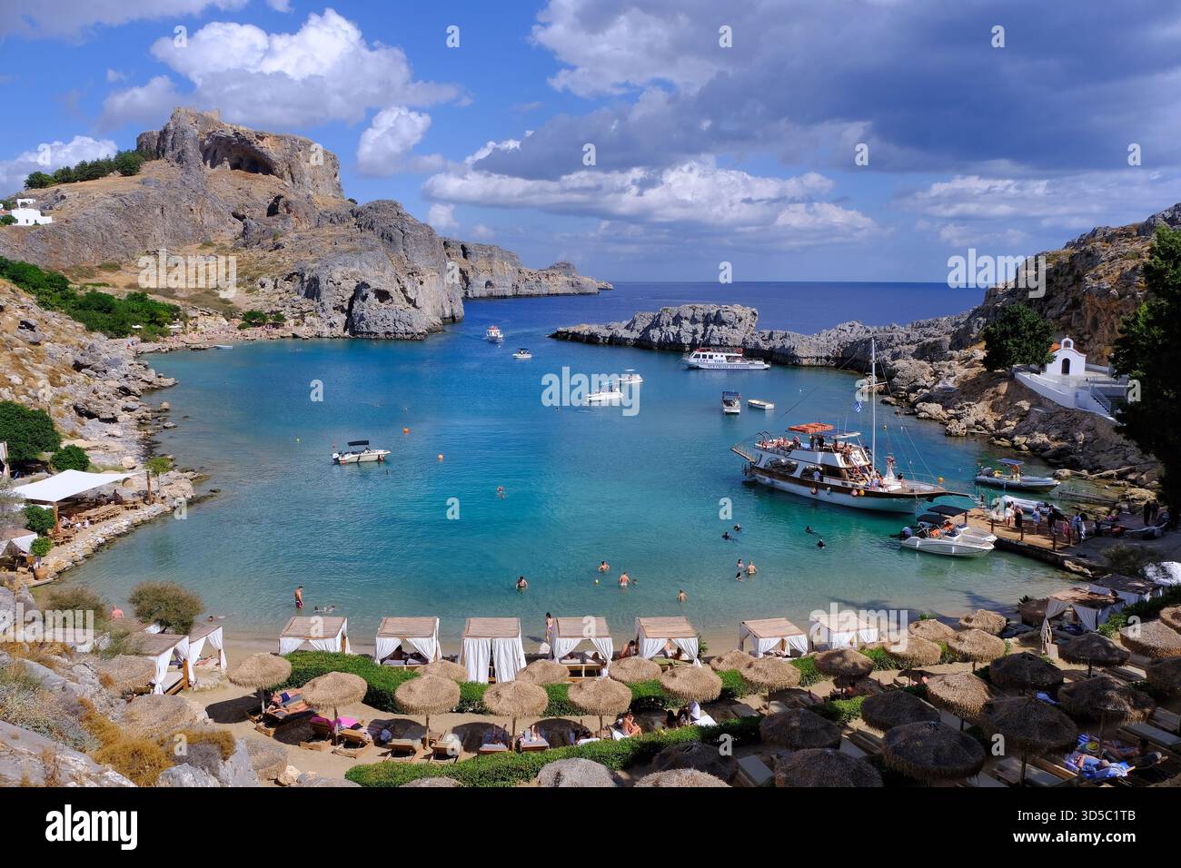 Lindos Rodi: Baia di San Paolo, cappella Agios Pavlos, castello dell'acropoli, spiaggia, nuotatori, ombrelloni, lettini e acque turchesi, Rodi, Grecia Foto Stock
