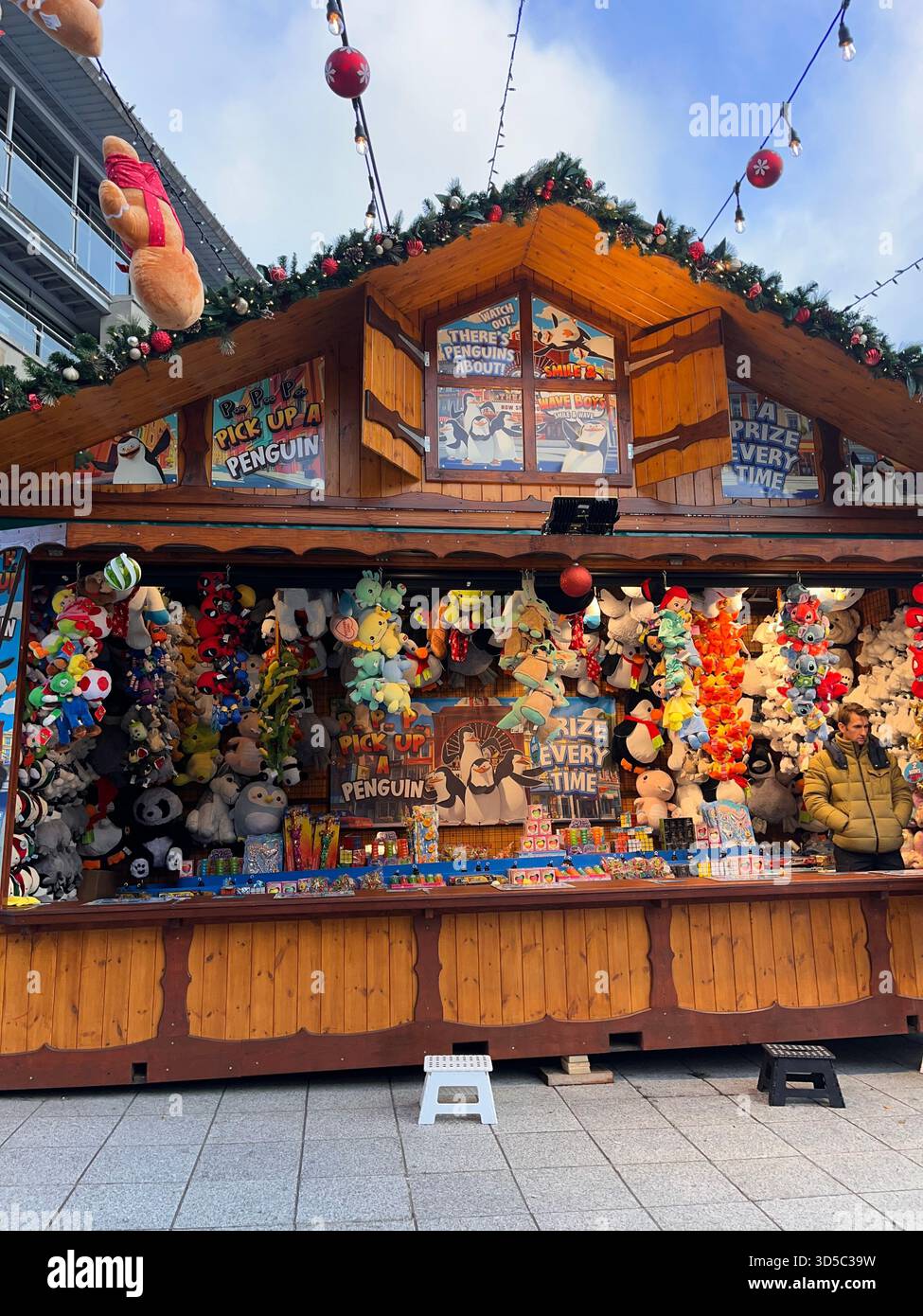 Colorato stand fieristico pieno di premi di peluche in un mercatino di Natale a Leeds, Inghilterra. Luminosa atmosfera carnevalesca con tradizionale legno - Immagine stock catturata con smartphone