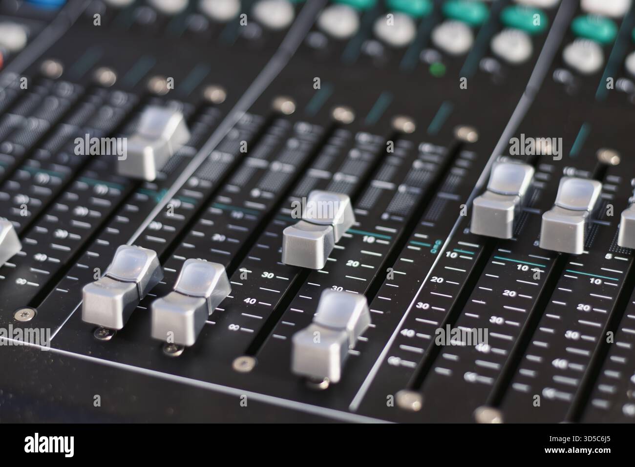Uno scatto ravvicinato di pulsanti di bilanciamento del fader scanalati su una scrivania di missaggio in uno studio di registrazione professionale, messa a fuoco selettiva con sfondo sfocato Foto Stock