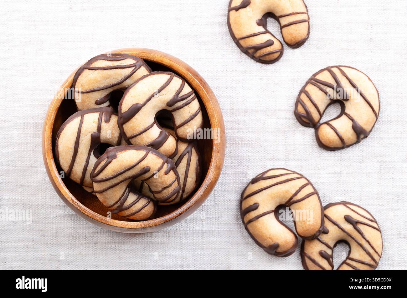 Biscotti di pasta frolla a forma di mezzaluna, in una ciotola di legno, su lino. Biscotti friabili, a base di burro, zucchero e farina. Foto Stock